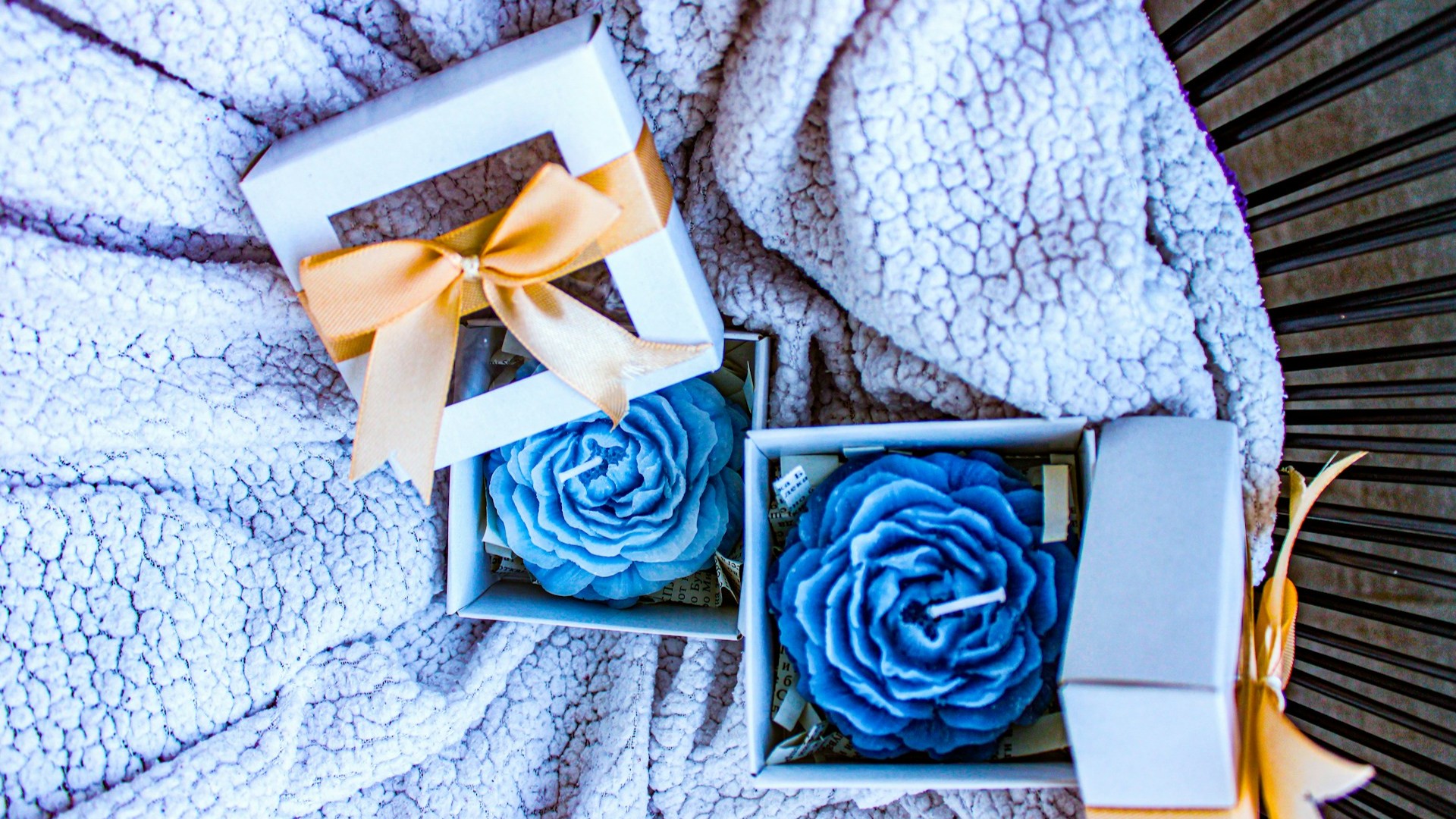 Twee blauwe roosvormige geurkaarsen in cadeaudoosjes als cadeau voor in huis