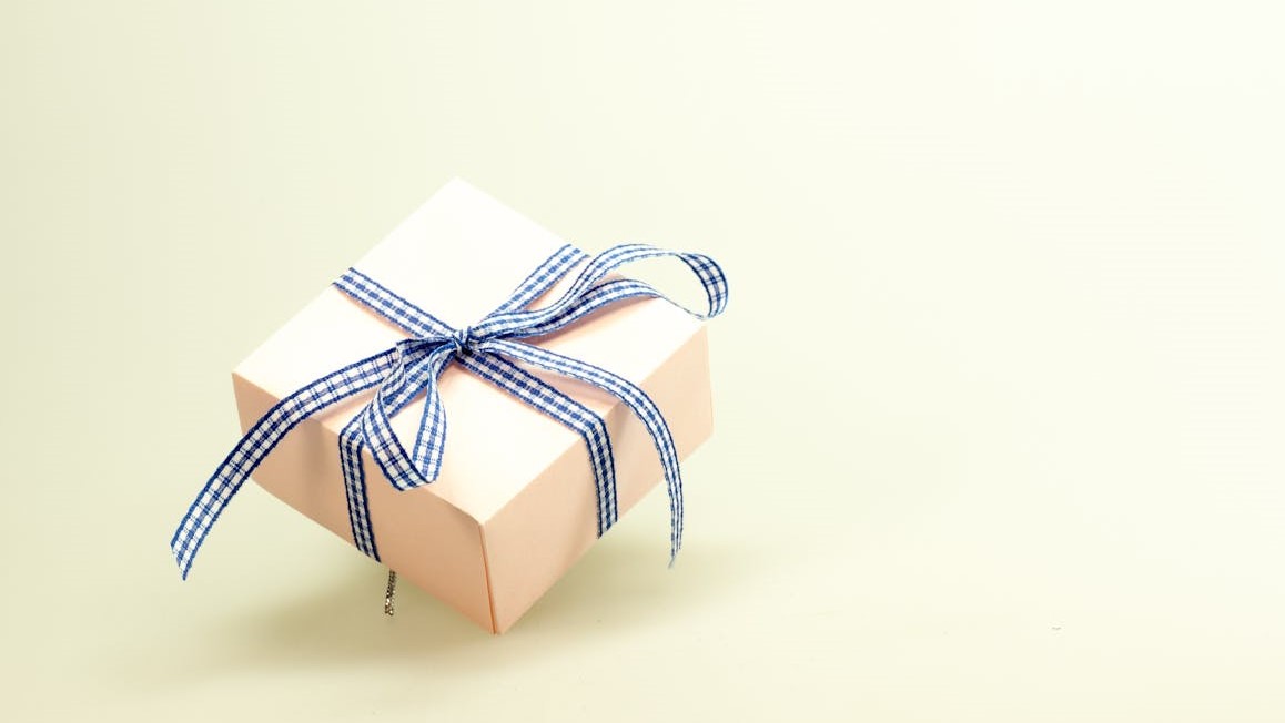 Warme cadeaus in stijlvol verpakt doosje met blauw geruit lint op lichte achtergrond